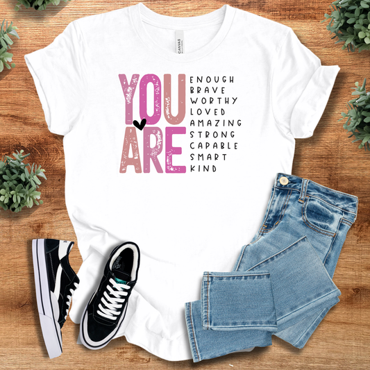You are Enough Tee in white with motivational words in bold typography. 100% cotton inspirational T-shirt for self-love and daily confidence.