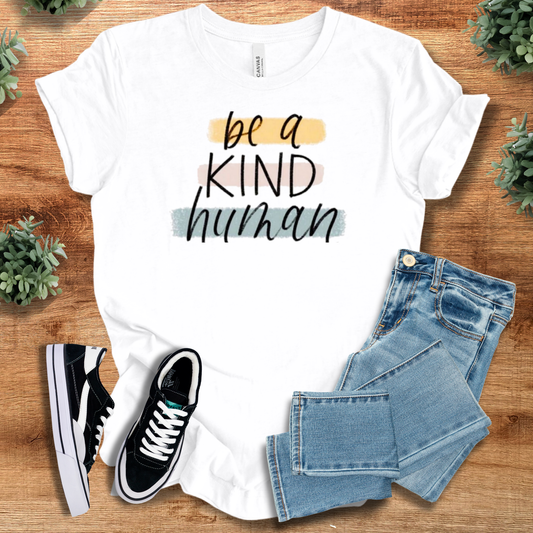 White 'Be a Kind Human' T-shirt in 100% cotton with casual fit, styled with jeans and sneakers. Inspirational kindness tee for everyday wear.