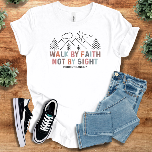 White t-shirt with motivational quote, black and white sneakers, and blue jeans on a wooden surface.